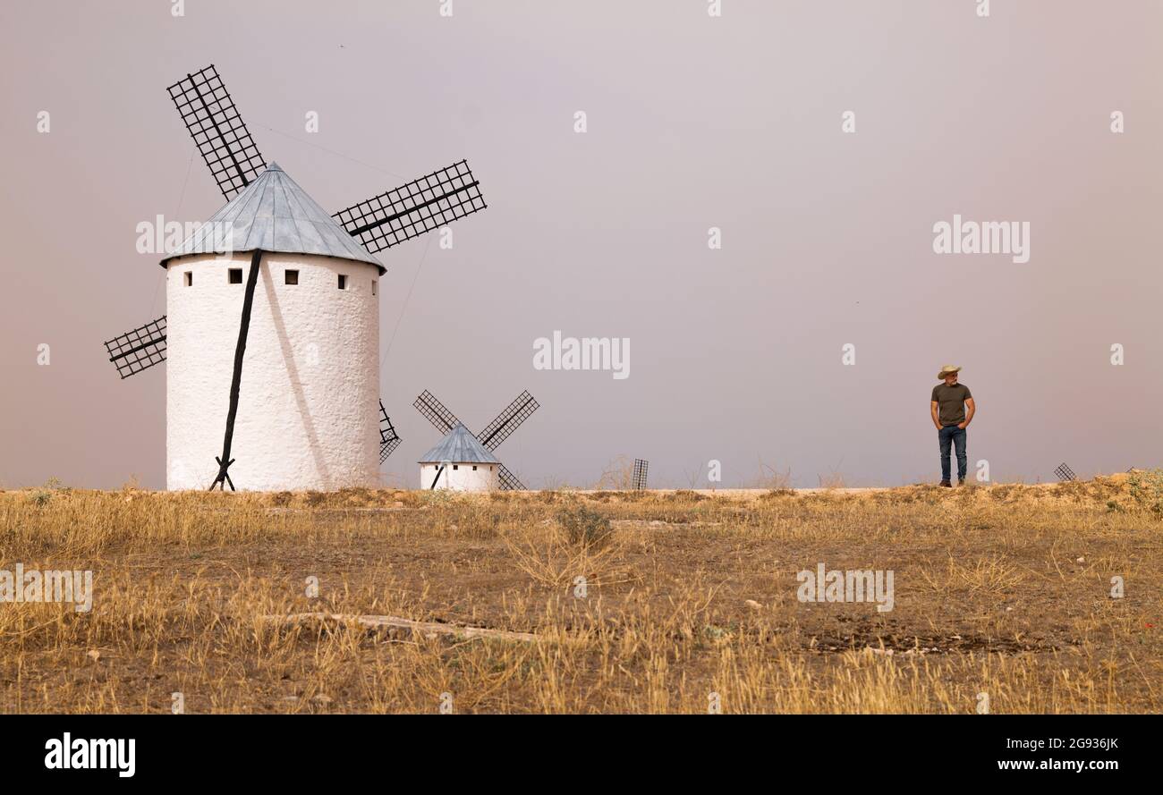 A man wearing a cowboy hat with windmills in the countryside Stock Photo