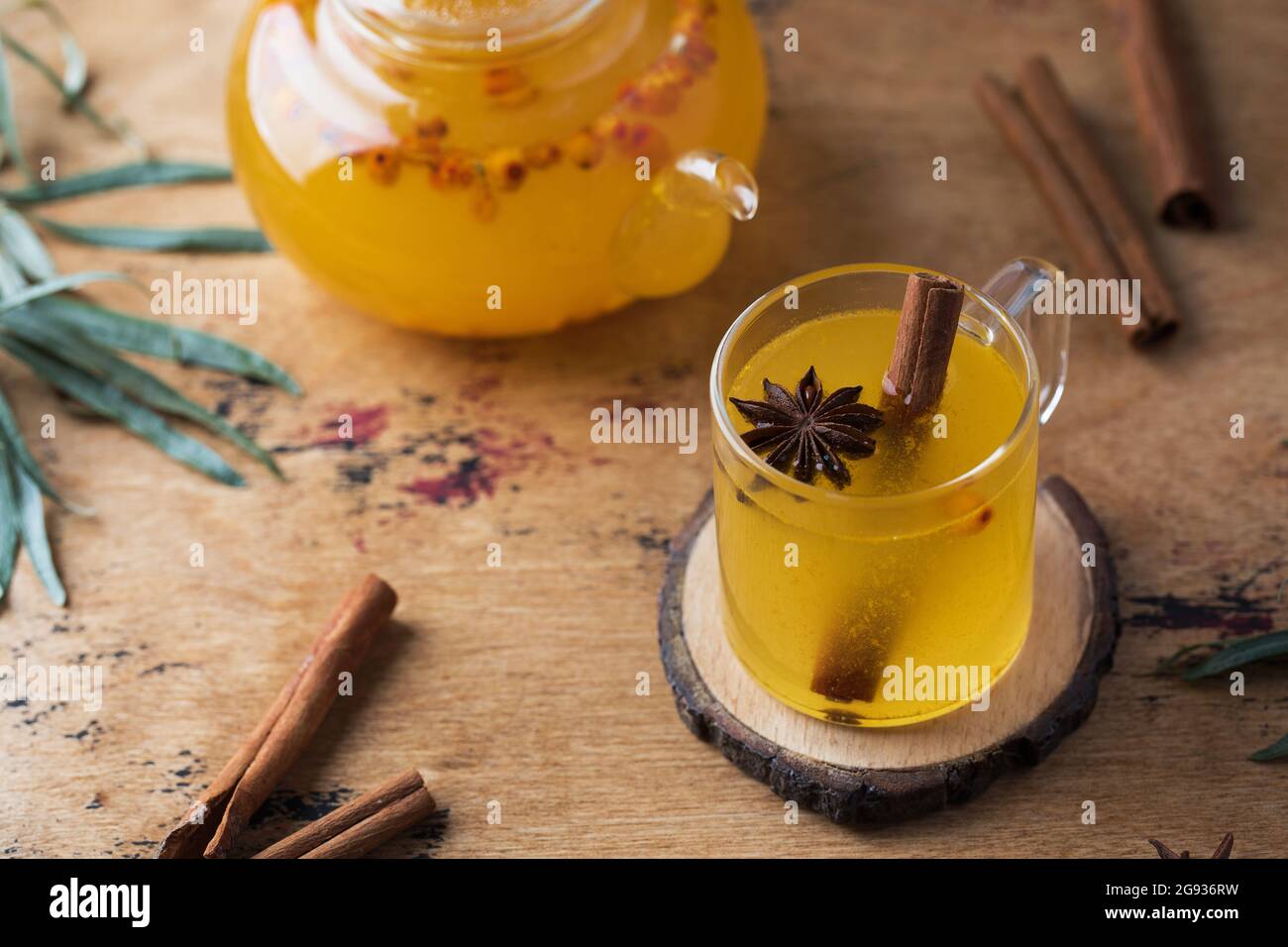 Autumn tea in a sea buckthorn mug with a cinnamon stick on a wooden background. Autumn mood. Stock Photo