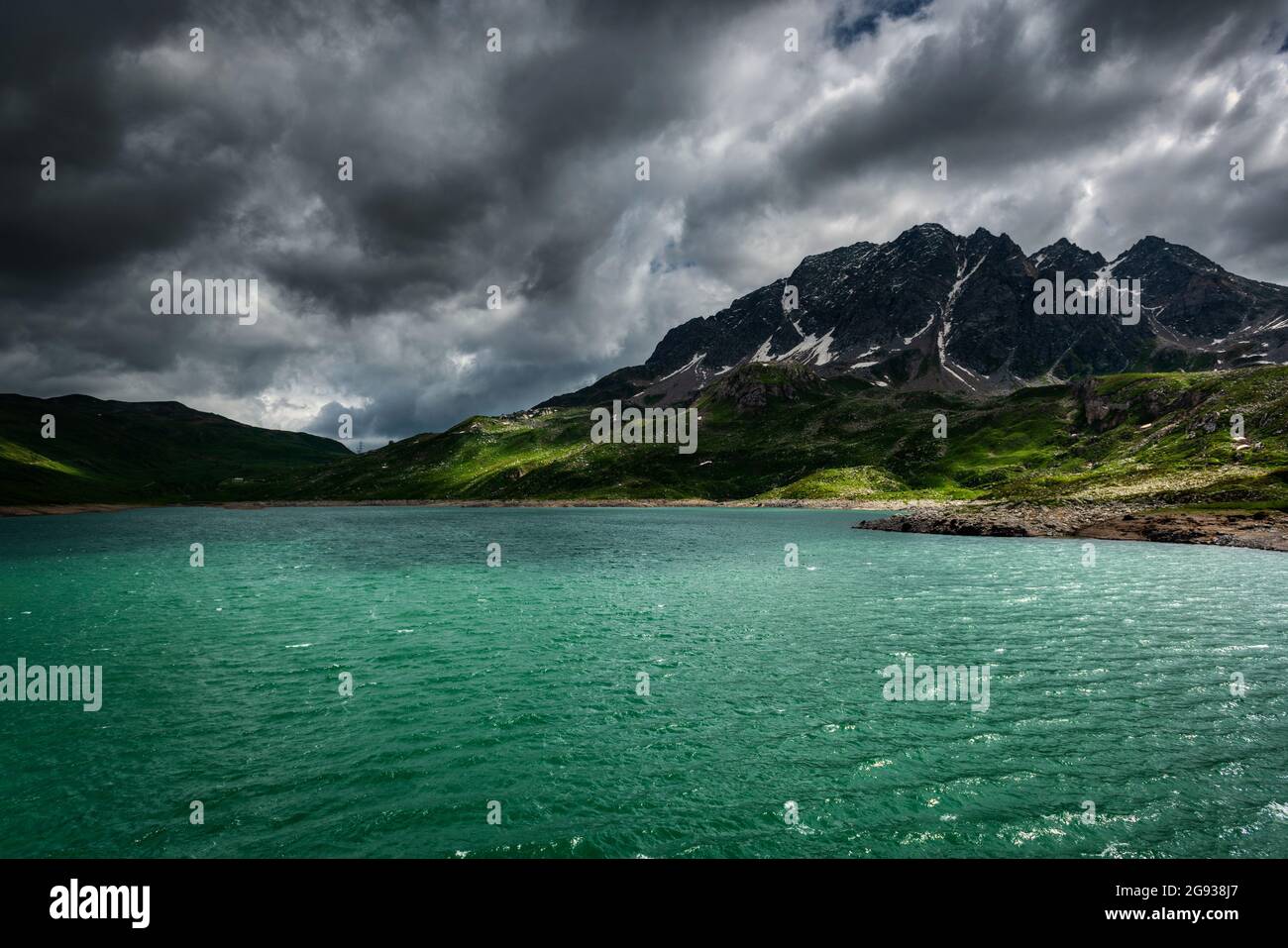 Lake in the Italian Alps with storm clouds in the sky and rays of Sun on the water Stock Photo