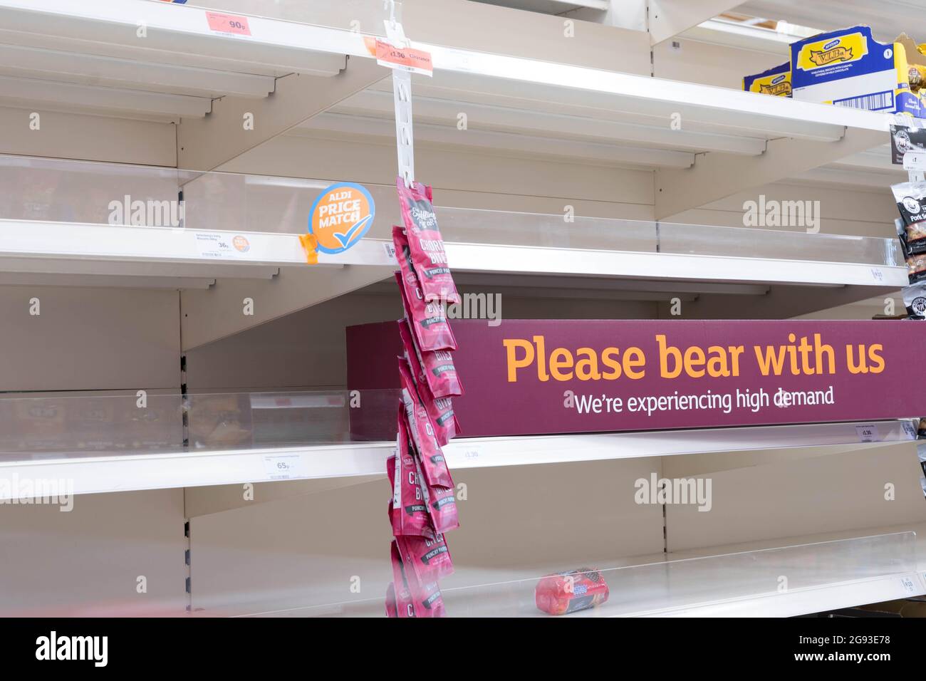 Empty shelves at Sainsbury's supermarket, showing message "Please bear