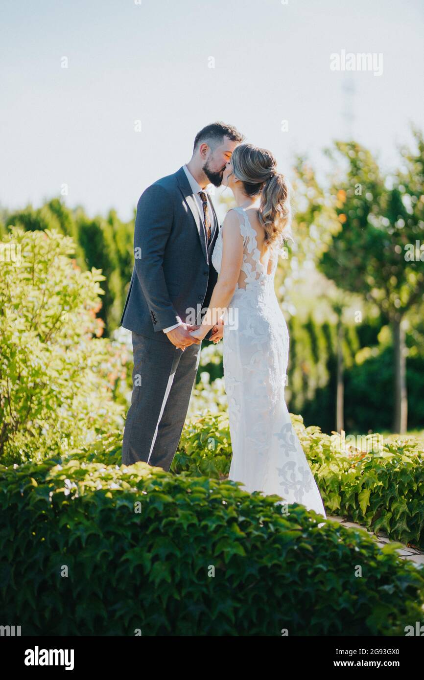 Beautiful bride and groom kissing in the garden Stock Photo - Alamy