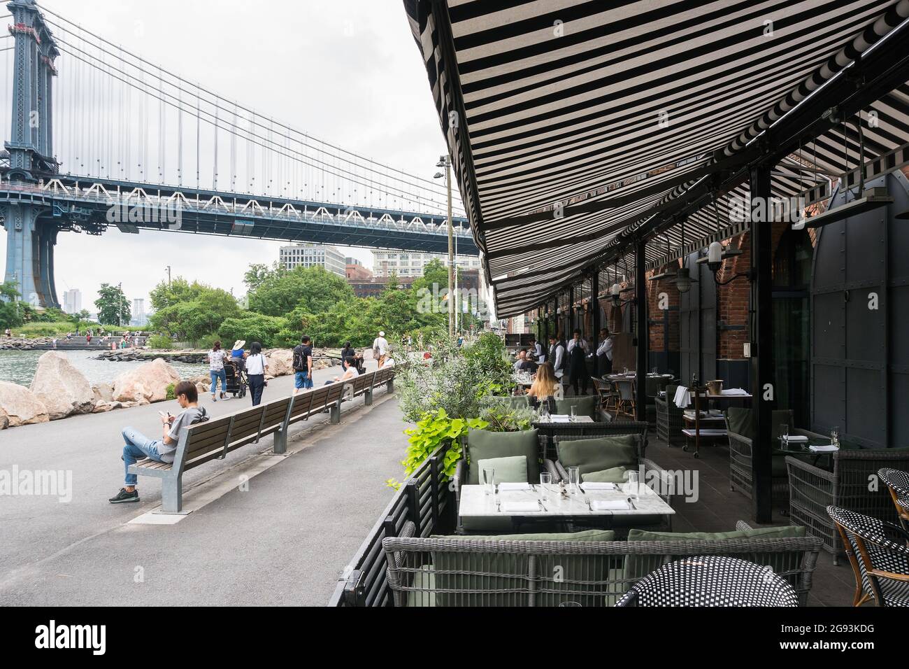 New York City, USA - August 6, 2019:People eat and chat while sitting in one of the many clubs of the Brooklin bridge park during a cloudy day. Stock Photo