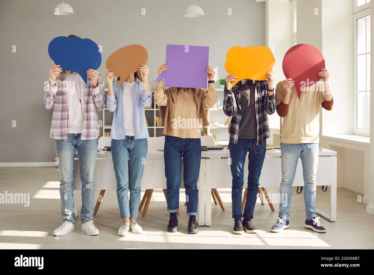 Group of college students covering faces with colorful paper mockup speech bubbles Stock Photo
