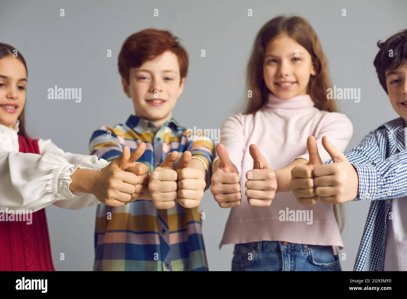 Studio group shot of happy satisfied little children giving thumbs up all together Stock Photo