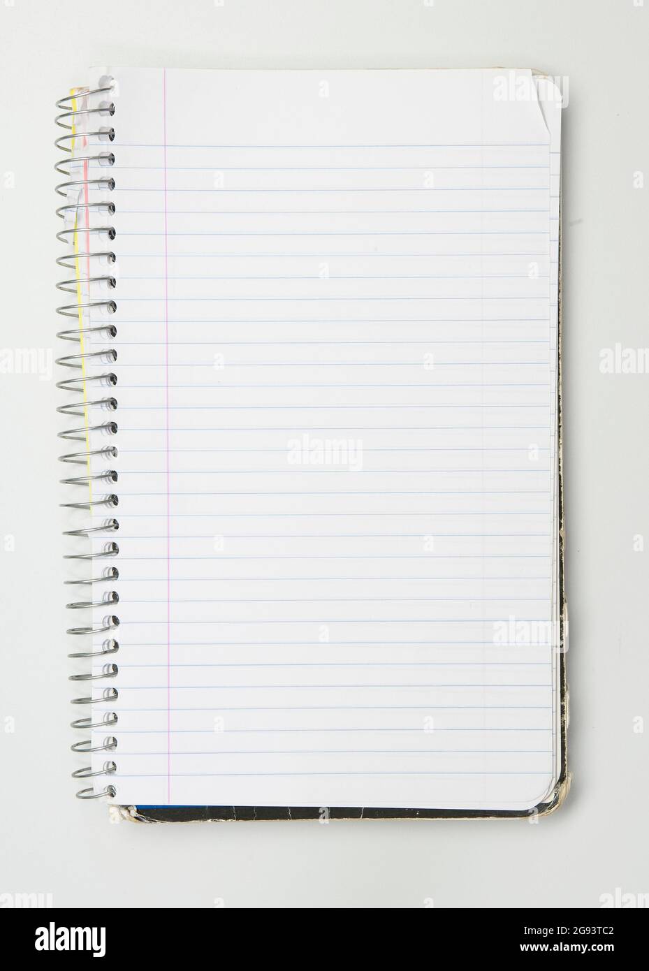 A worn used wire bound notebook opened to a blank lined page Stock Photo