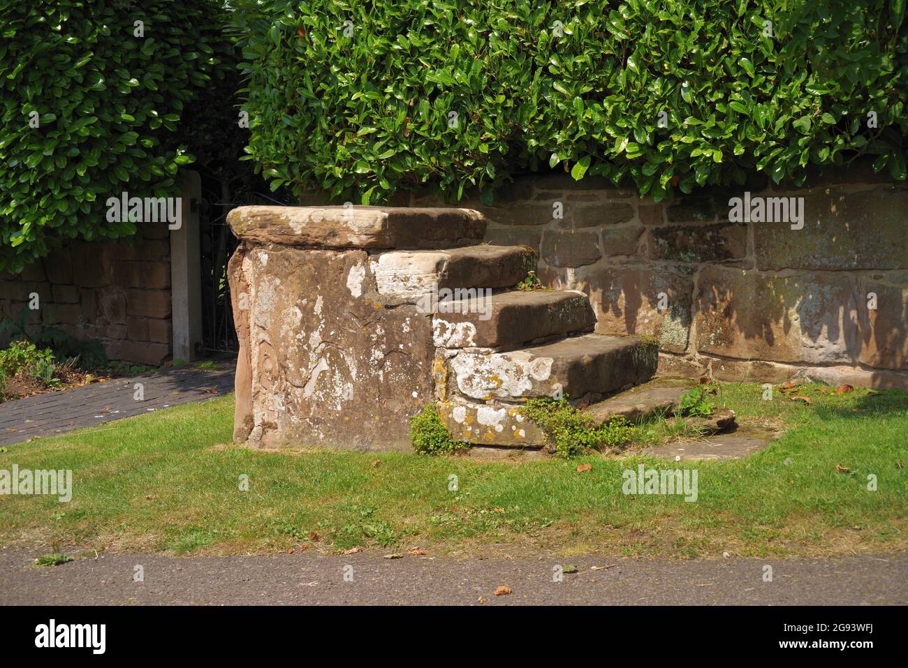 five step Georgian masonry equine horse mounting block on a village green Stock Photo