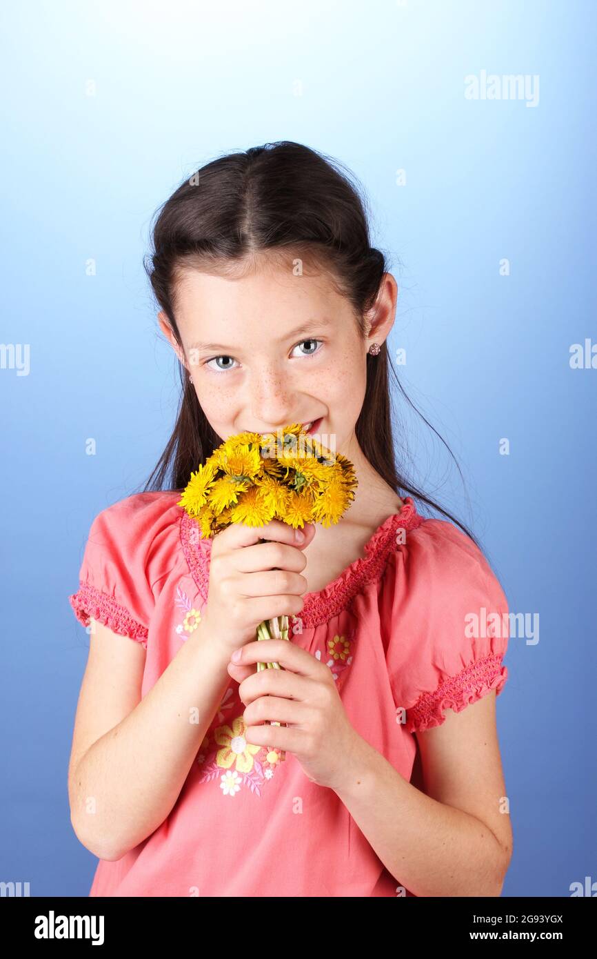 Portrait of beautiful little girl with dandelions on blue background ...