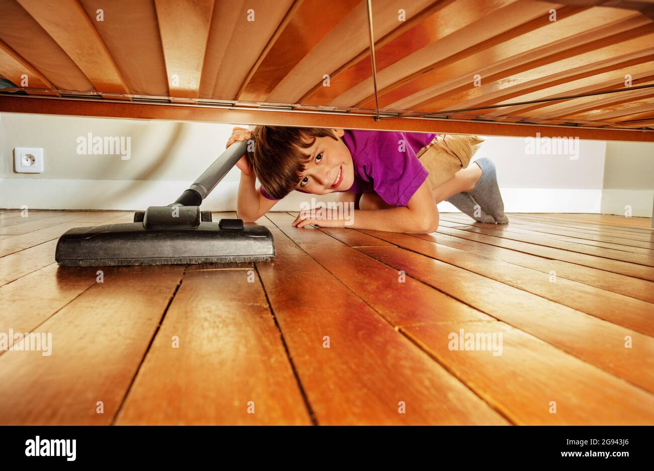 Boy vacuum clean under the bed in his room smiling Stock Photo Alamy