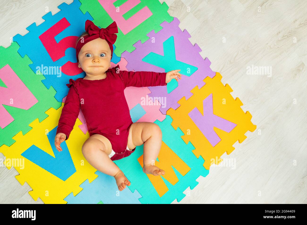 Little baby girl lay on the color ABC carpet Stock Photo