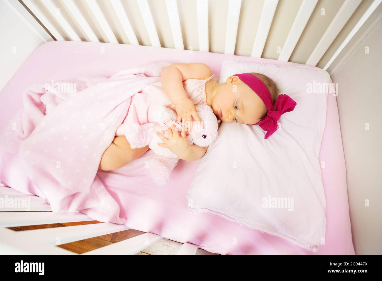 baby lay in crib bed with calm expression hug toy Stock Photo Alamy
