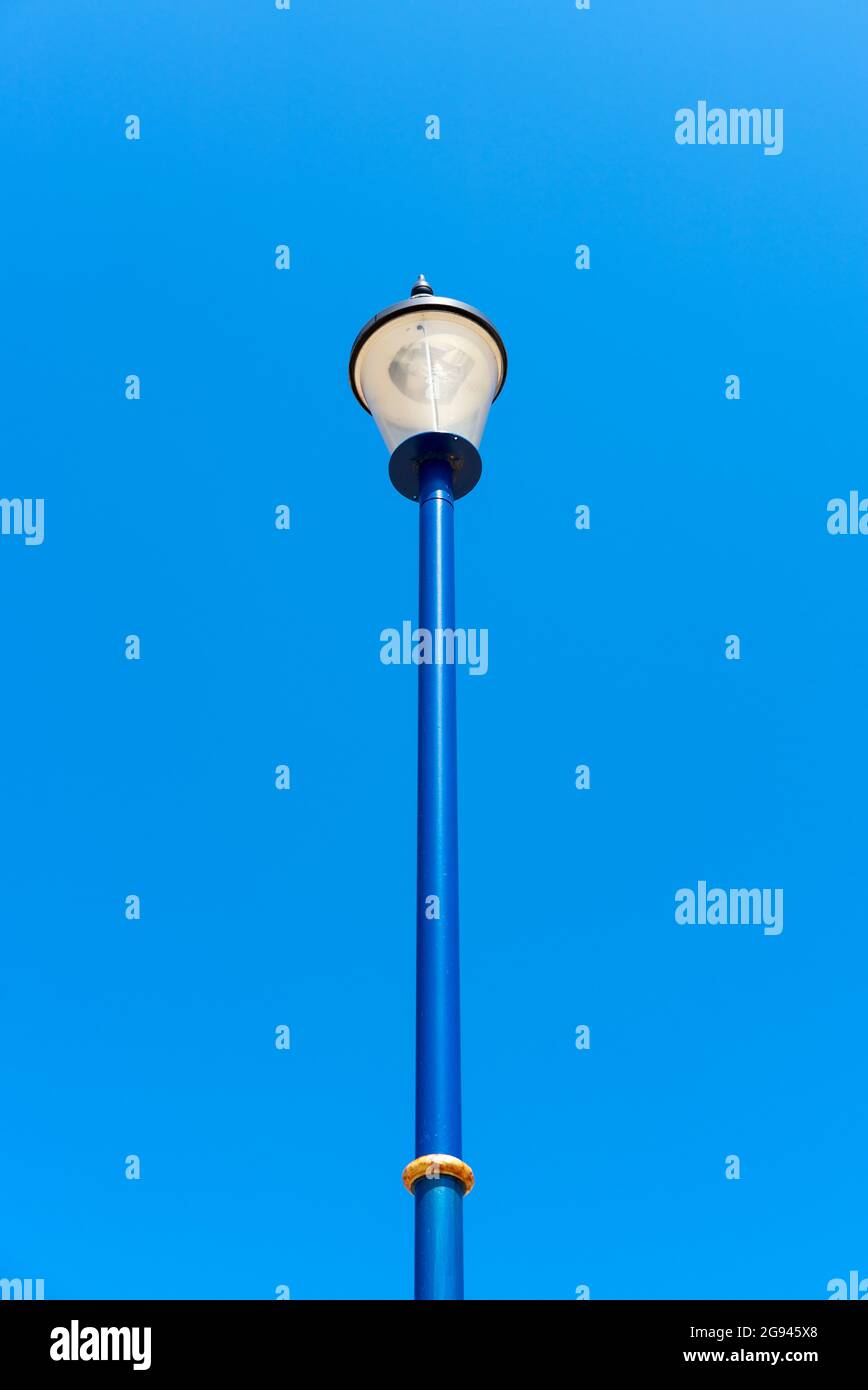 Portrait view of a steel lamp post set against a clear blue sky, Sutton
