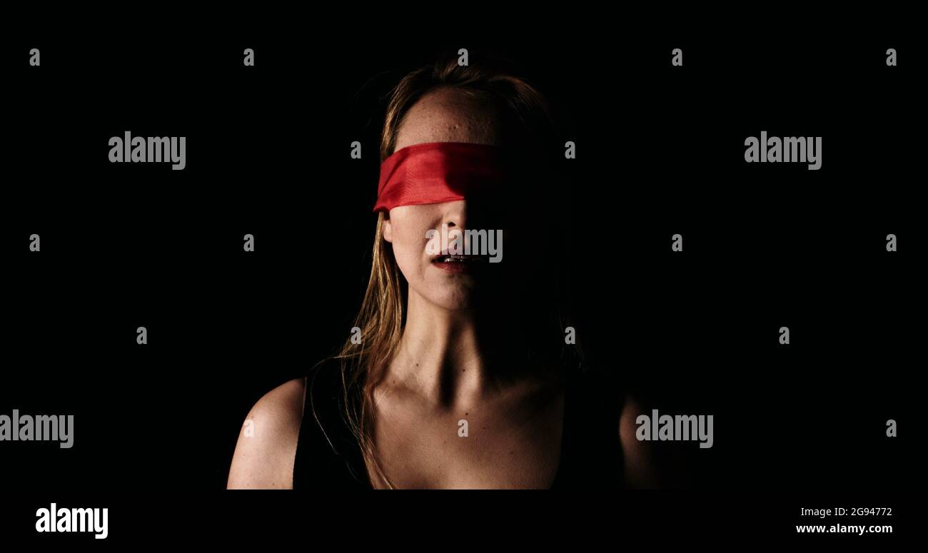 Young scared woman with red ribbon on her eyes screaming loud. Stock Photo
