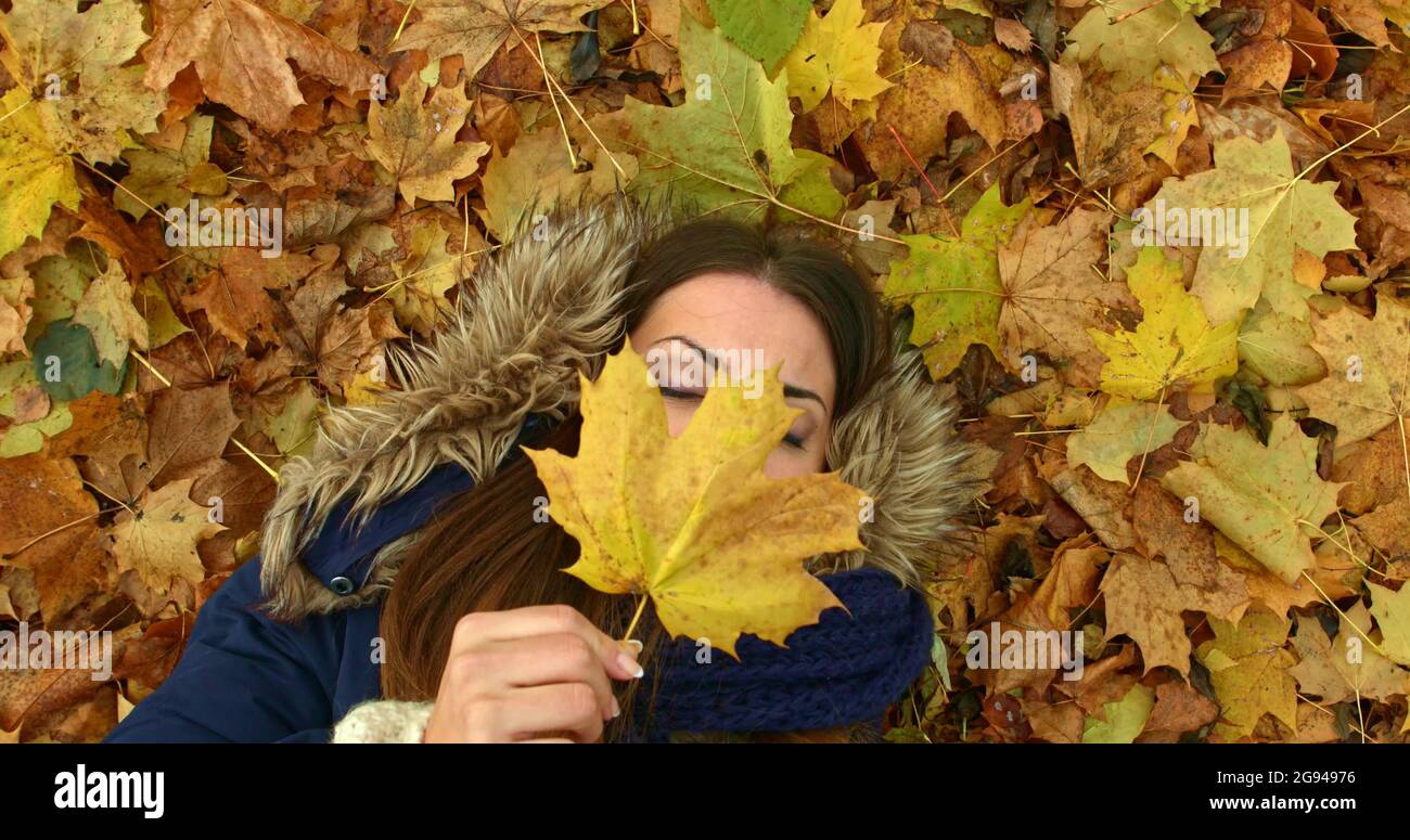Young woman lying in autumn park with leafs. Stock Photo