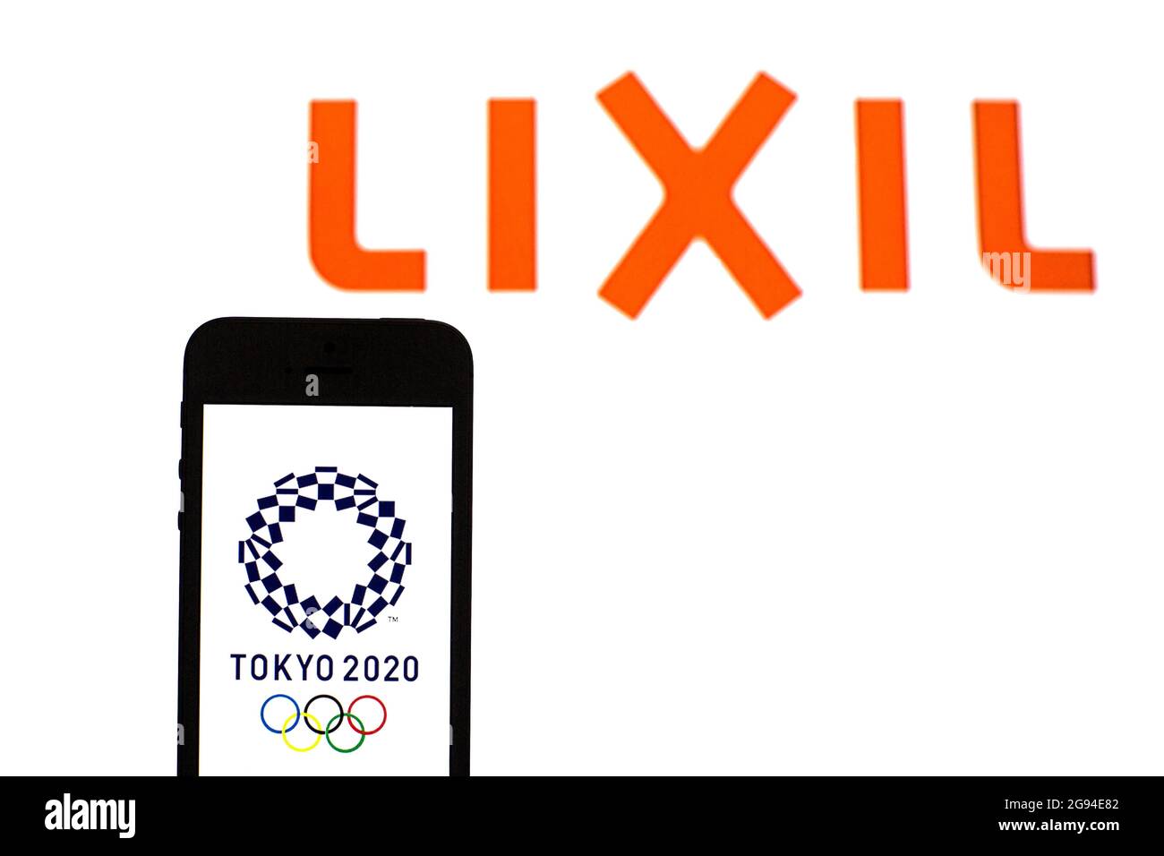 In this photo illustration a Tokyo 2020 Olympic Games logo seen displayed on a smartphone with a Lixil Group Corporation logo in the background. Stock Photo