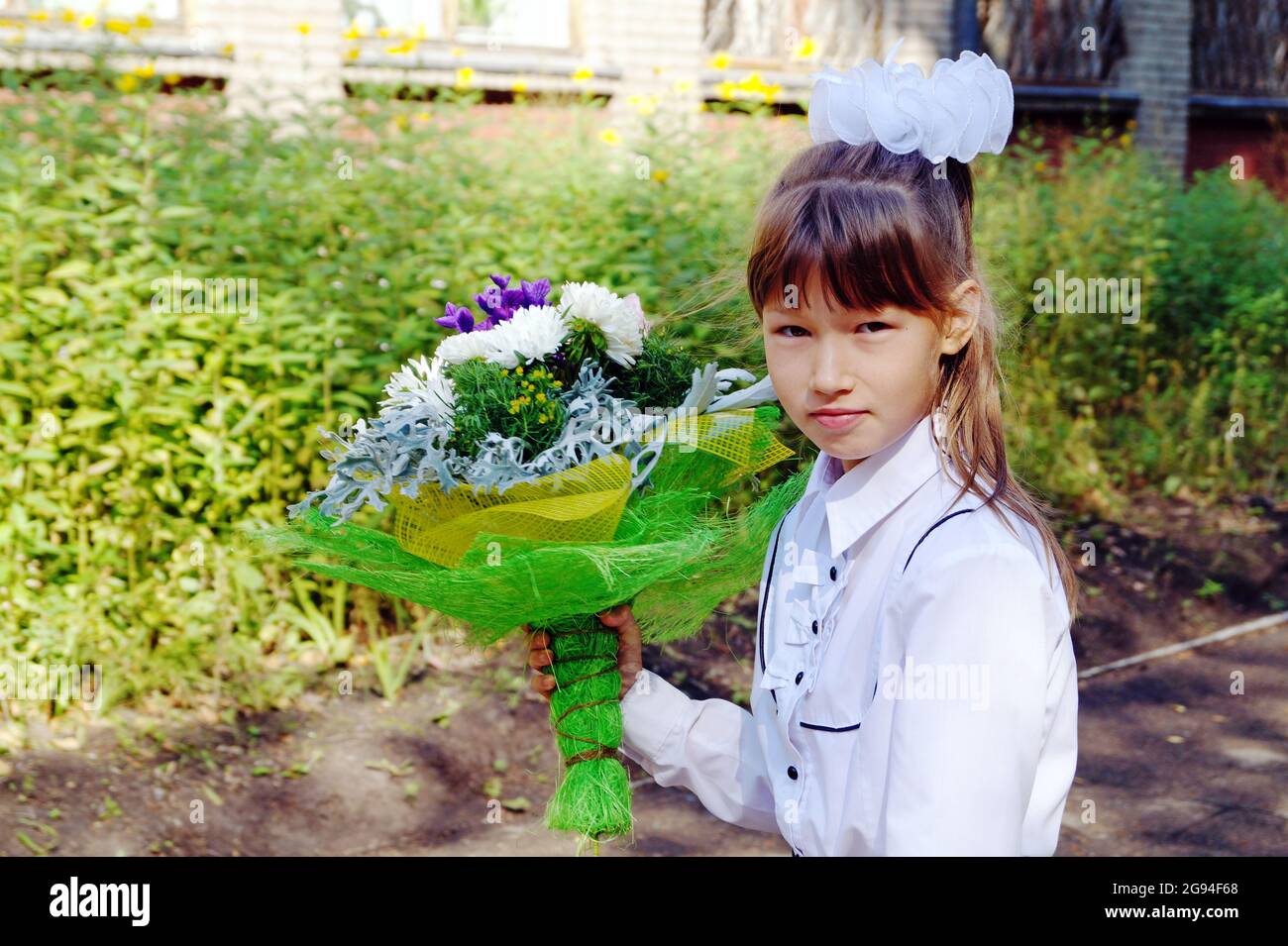 A girl with a bouquet of flowers and a briefcase goes on September 1 Stock Photo