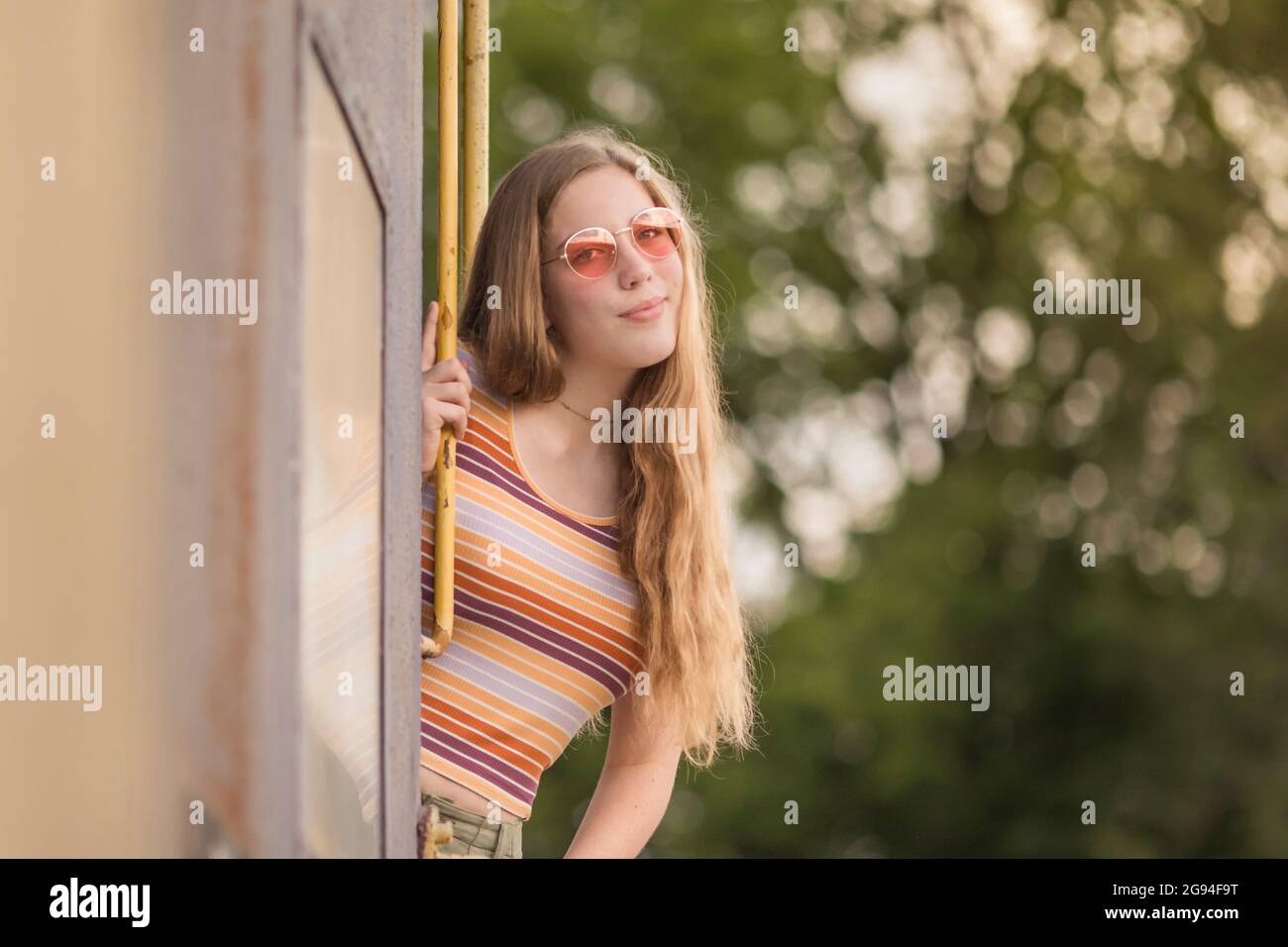 Retro seventies style teen girl in rose colored glasses on train Stock Photo