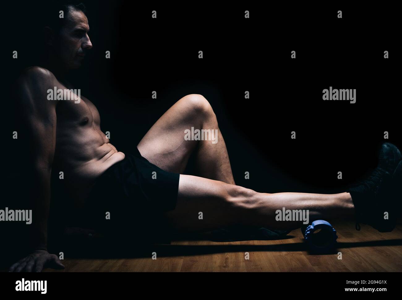 Man sitting on the floor doing stretching exercises Stock Photo