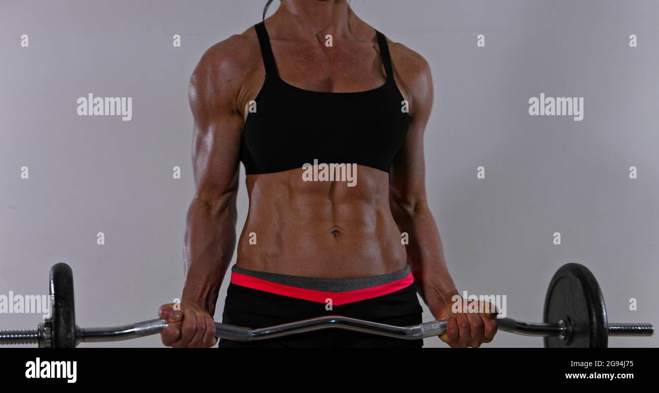 Muscular woman is lifting barbells for workout biceps. Bodybuilding. Stock Photo