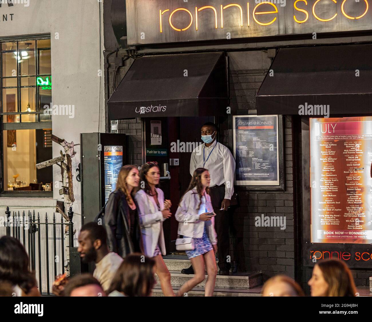 Security guard with mask and people walking on street in Soho, London, United Kingdom. Stock Photo