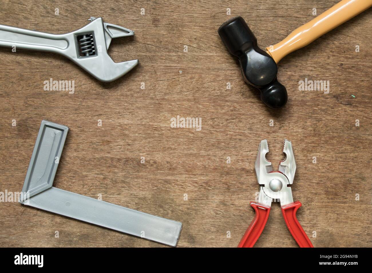 Toy equipment tool (hammer, mschinist square, wrench, pliers) with copy space on wood background Stock Photo