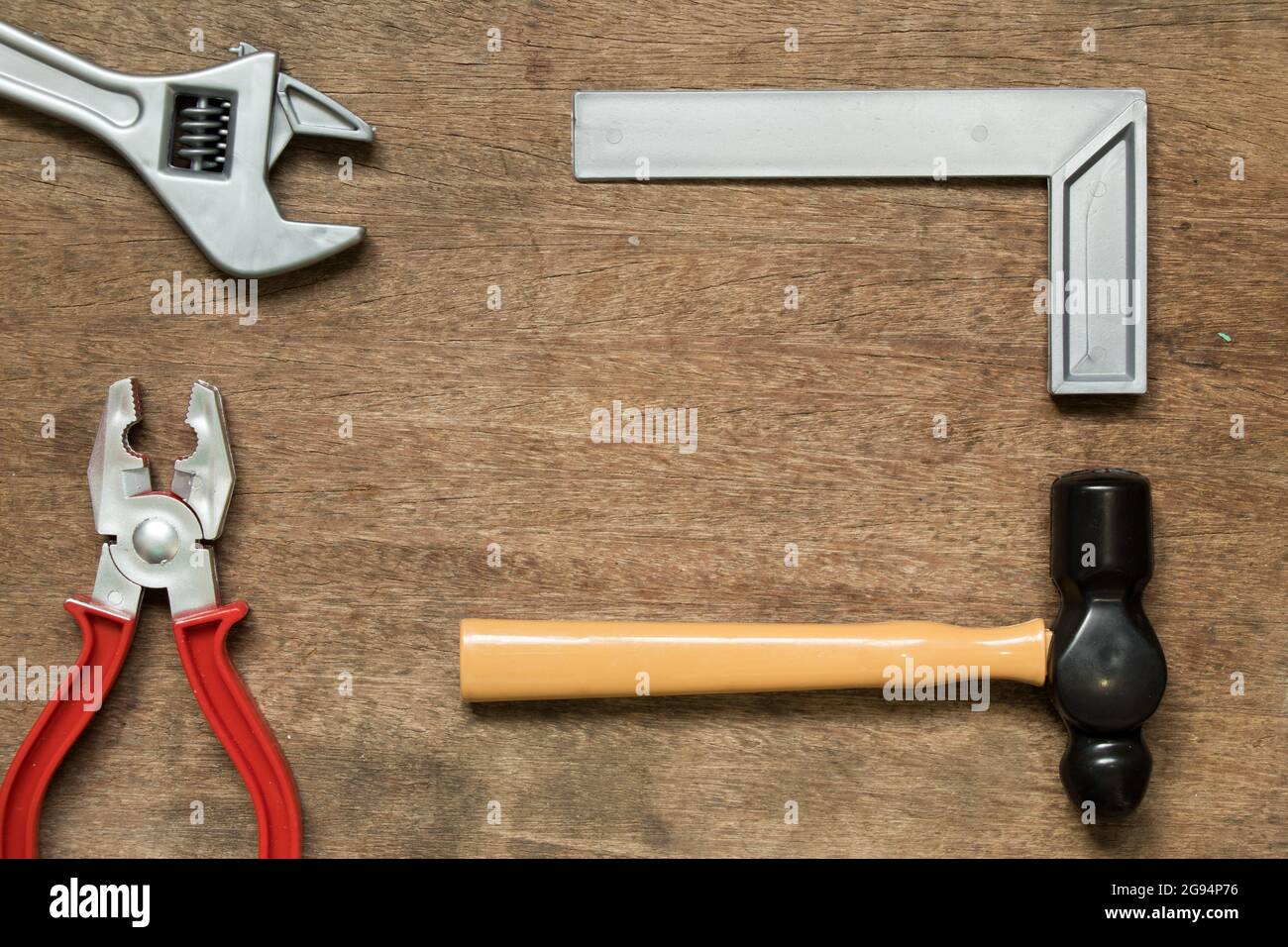 Toy equipment tool (hammer, mschinist square, wrench, pliers) with copy space on wood background Stock Photo