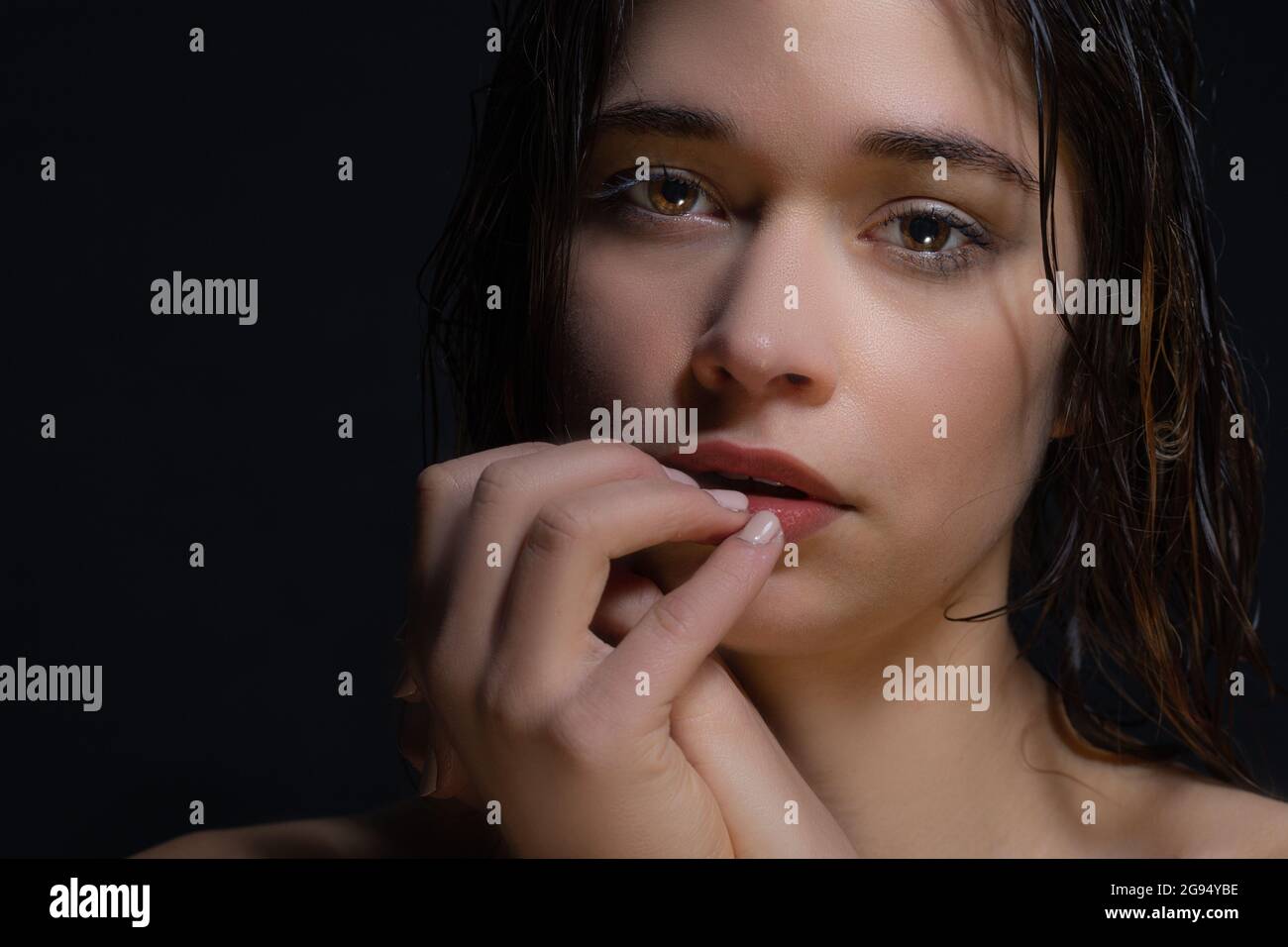 A sad young woman looks at the camera blankly. The woman is depressed due to loneliness and isolation. The Mental Effects of Isolating and Closing Your Home During Quarantine. Woman's face on black. Stock Photo