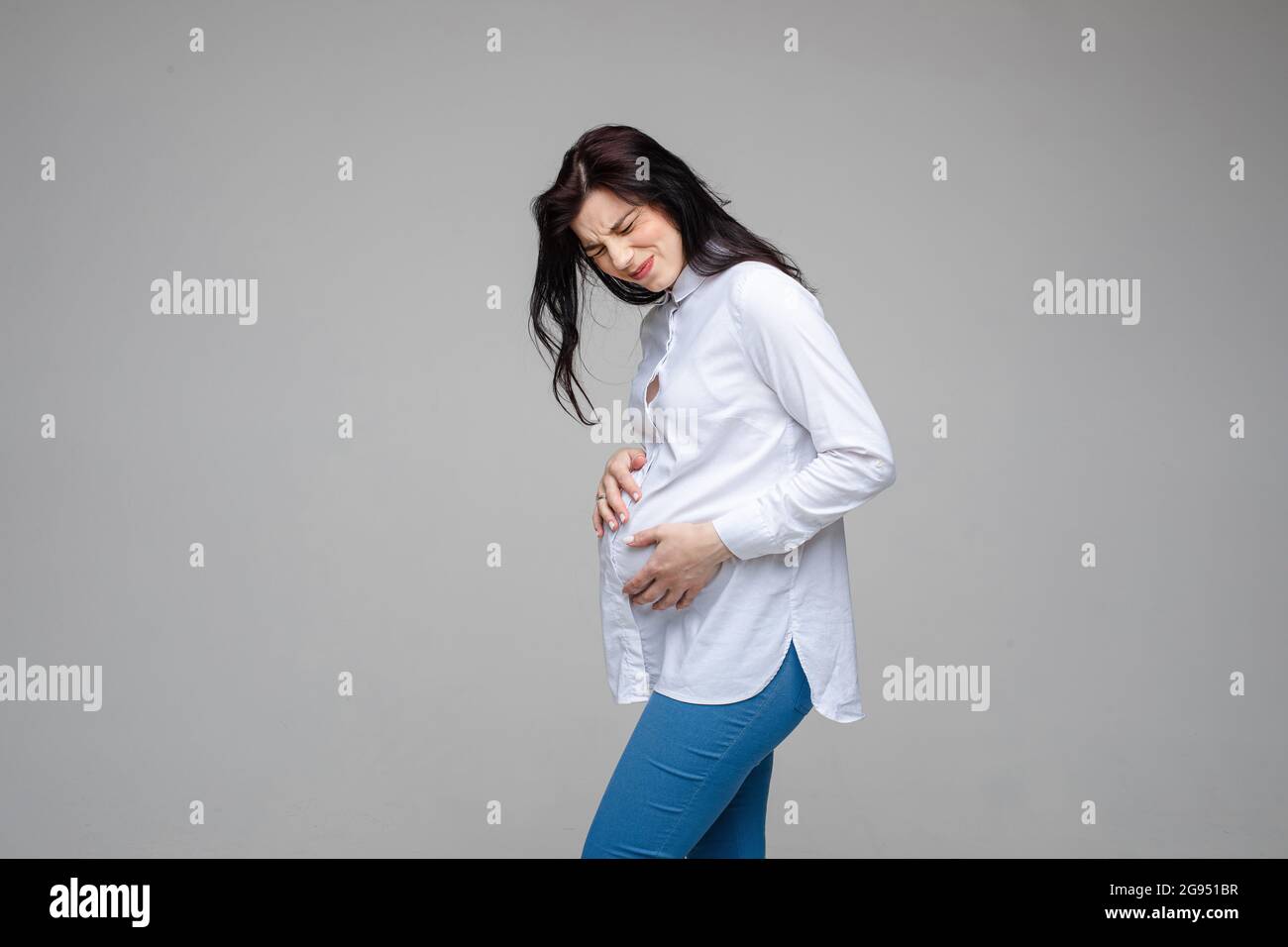 Beautiful female expecting baby, touch pregnant belly feeling pain on