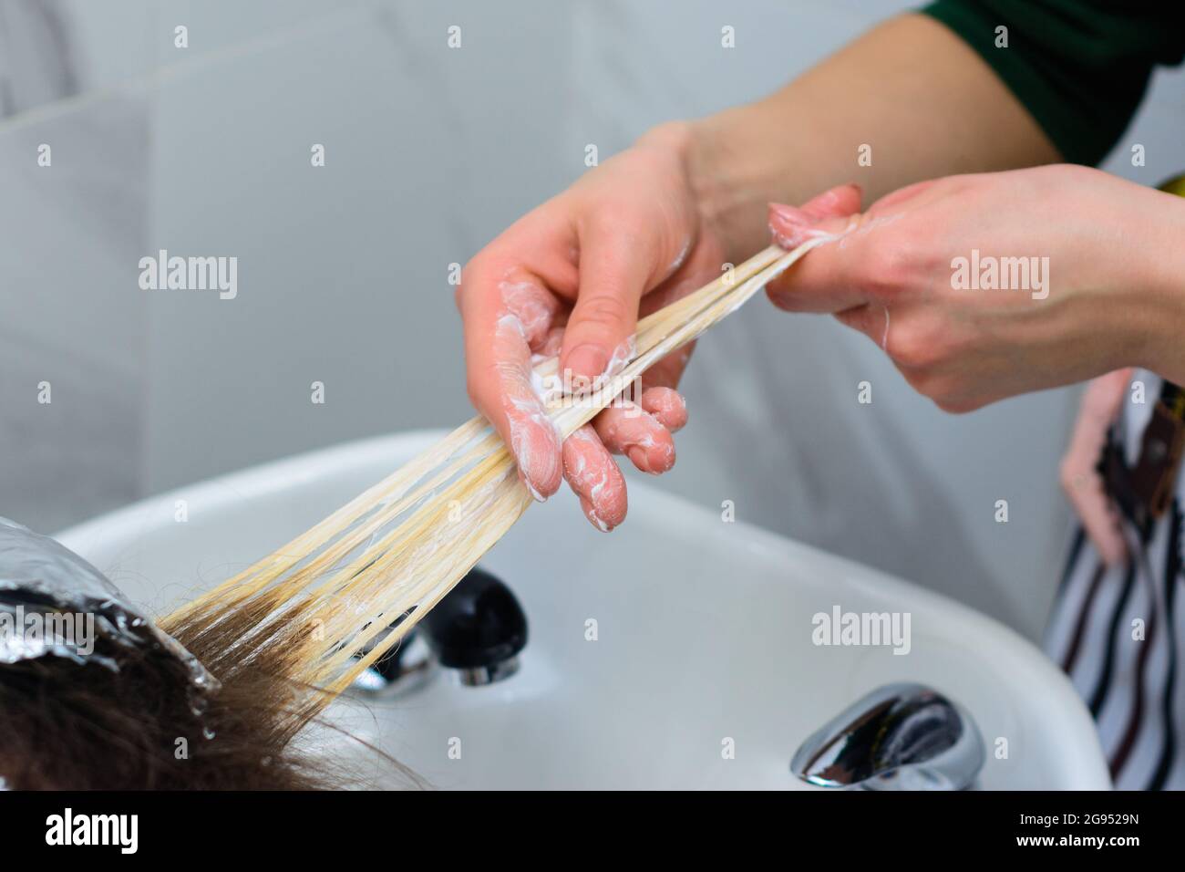 Washing hair dye from a hairdresser, removing foil from hair. new Stock