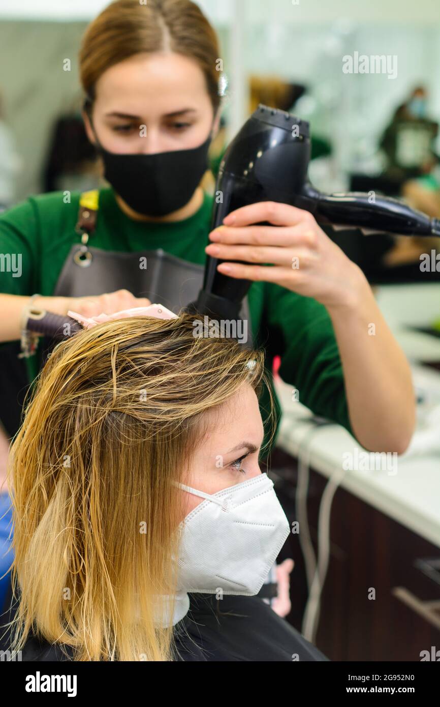 The stylist uses a hair dryer to style the hair after coloring. new
