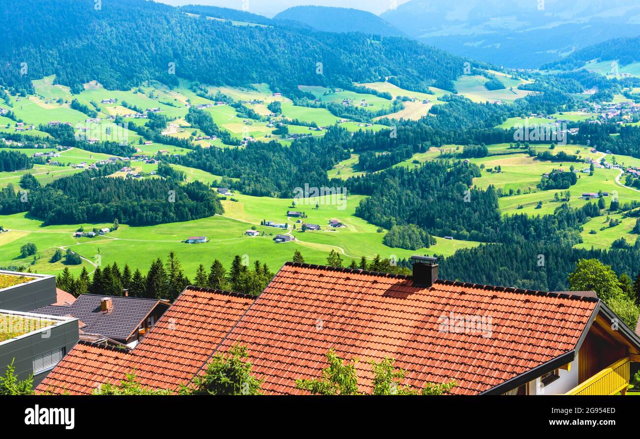 Scenery of rustic houses in Alpine green valley, Austria, Europe. Roofs in traditional village on background of mountain forest. Landscape of rural te Stock Photo