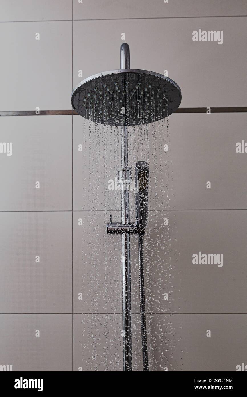 Shower with a tiled background in the bathroom. Water flies from chrome