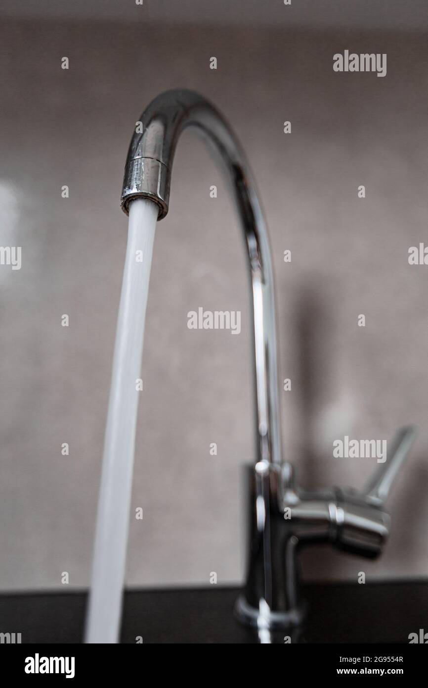 Water flows from the silver faucet to the sink. Stainless steel water