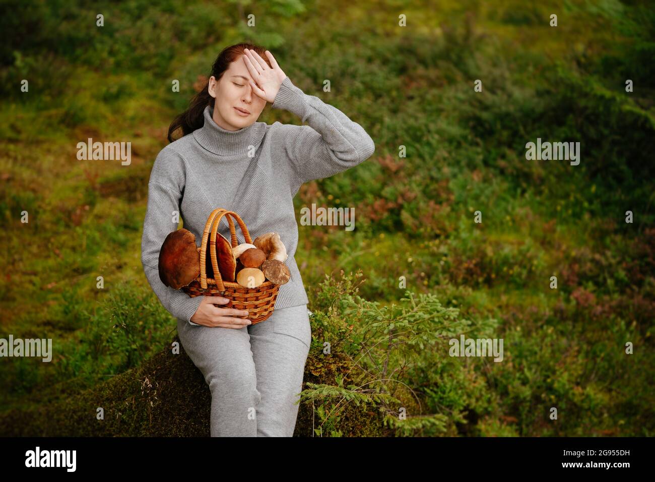 Woman is resting on the green grass in the forest with mushrooms Stock Photo
