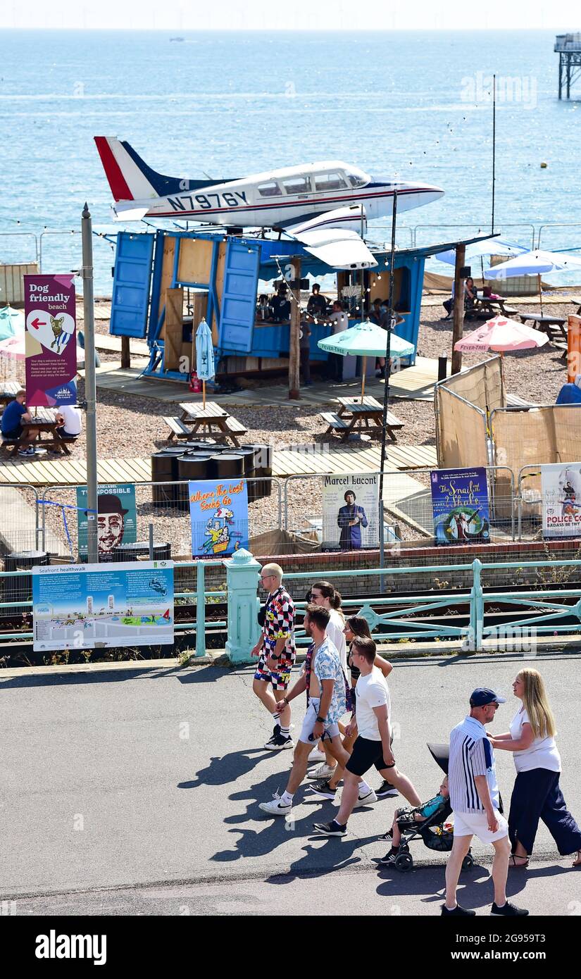 Brighton UK 24th July 2021 - Who parked that plane there as partygoers make their way to the On The Beach festival in Brighton in hot sunshine today .  : Credit Simon Dack / Alamy Live News Stock Photo