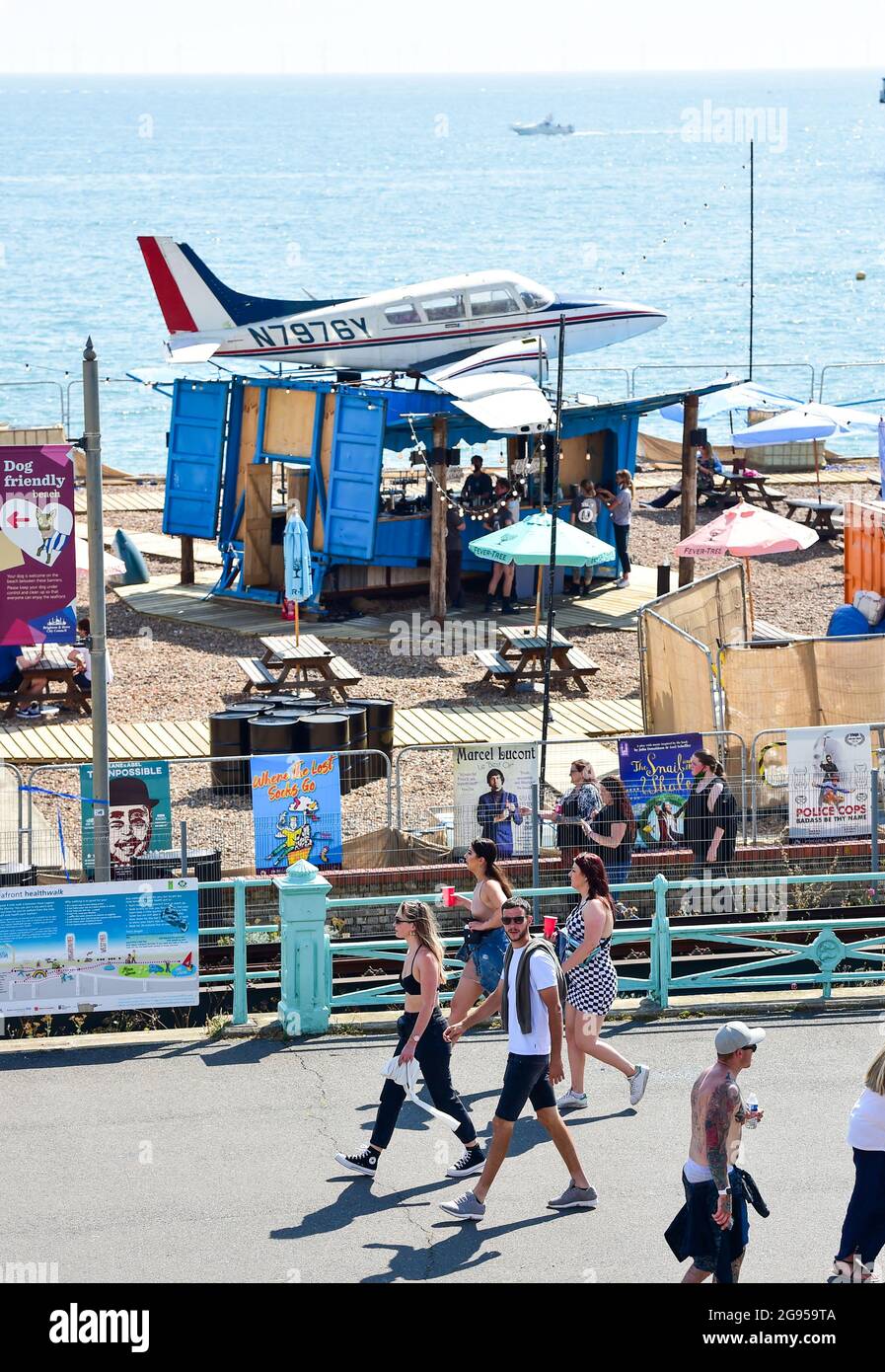 Brighton UK 24th July 2021 - Who parked that plane there as partygoers make their way to the On The Beach festival in Brighton in hot sunshine today .  : Credit Simon Dack / Alamy Live News Stock Photo