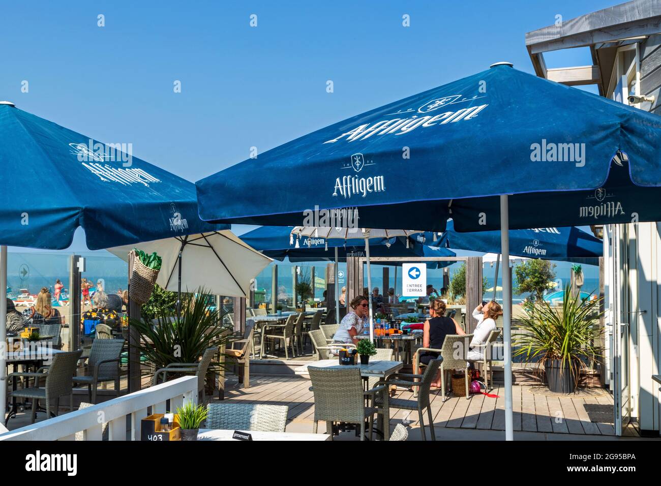 Seaside visitors relaxing at a beach pavilion and enjoying the sunny
