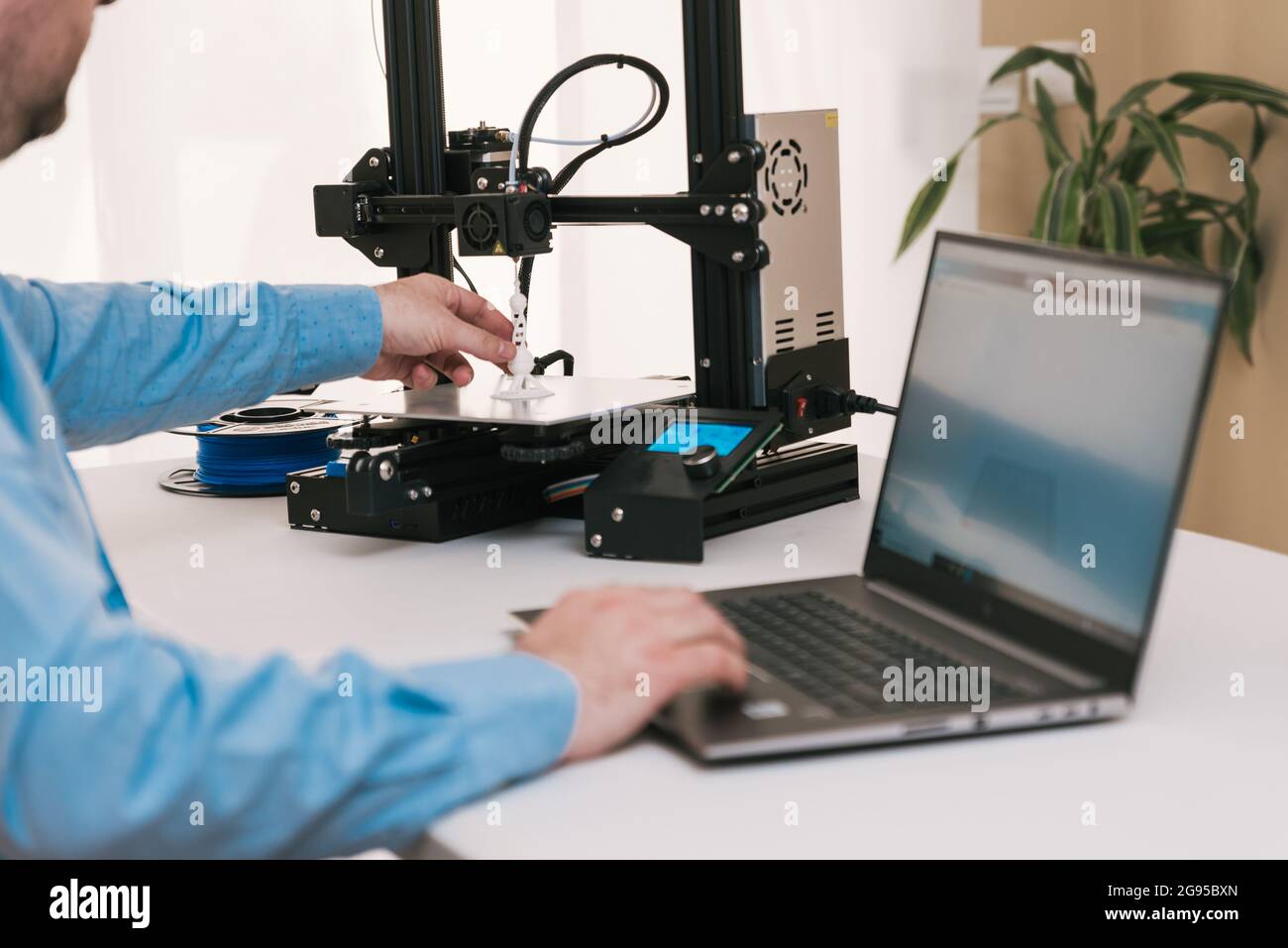 Young engineer in the lab adjusting a 3D printer's components Stock Photo