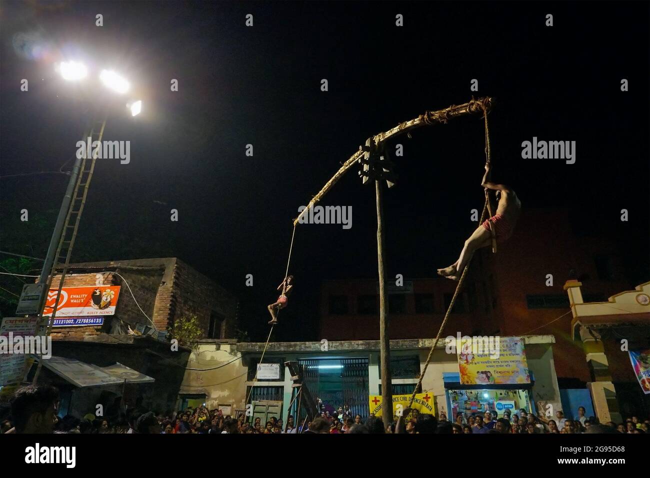 KOLKATA, WEST BENGAL, INDIA - 15 APRIL 2018: Two Hindu devotees are hanging from pole in air, at night. Religious sports for festival called Charhak o Stock Photo