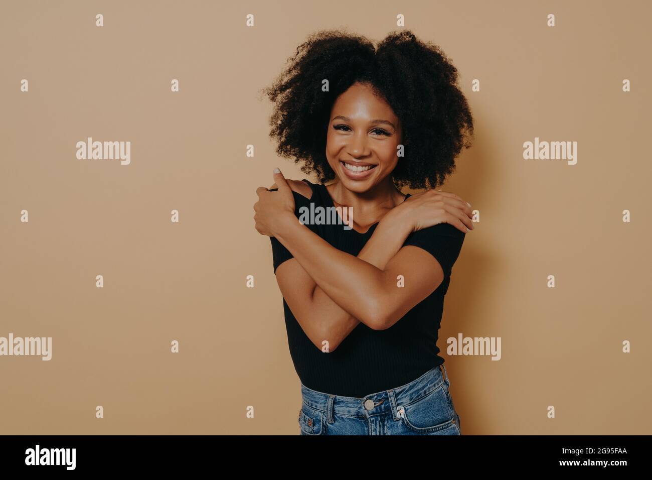 Image of beautiful pleased young dark skinned female with voluminous afro hairstyle Stock Photo