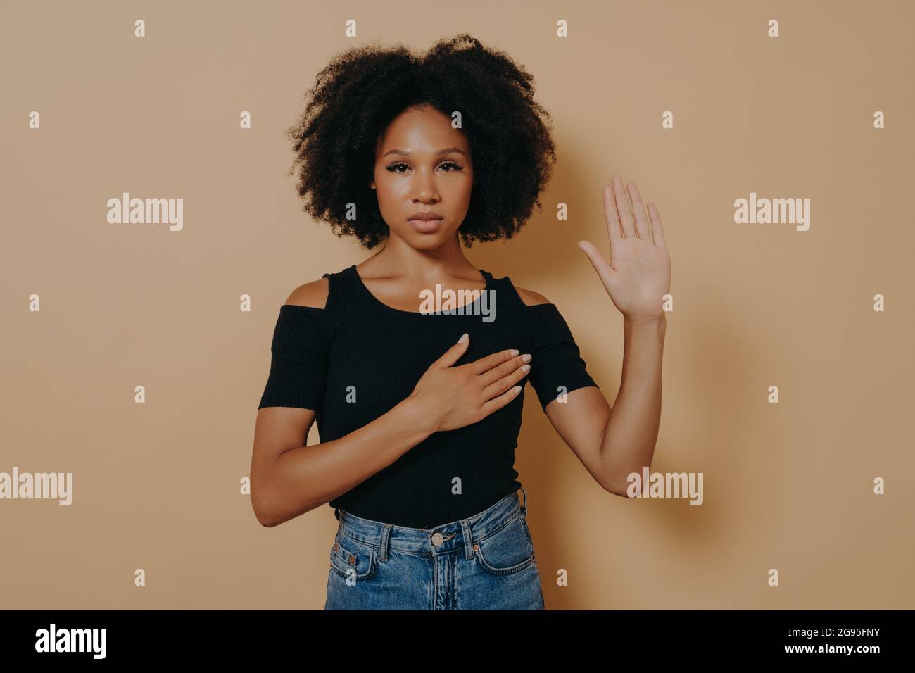 Dark skinned woman wearing casual shirt and jeans , doing loyalty promise oath Stock Photo