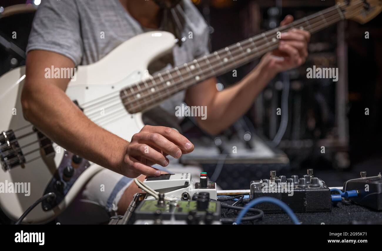 A male guitarist setting up guitar audio processing effects on stage