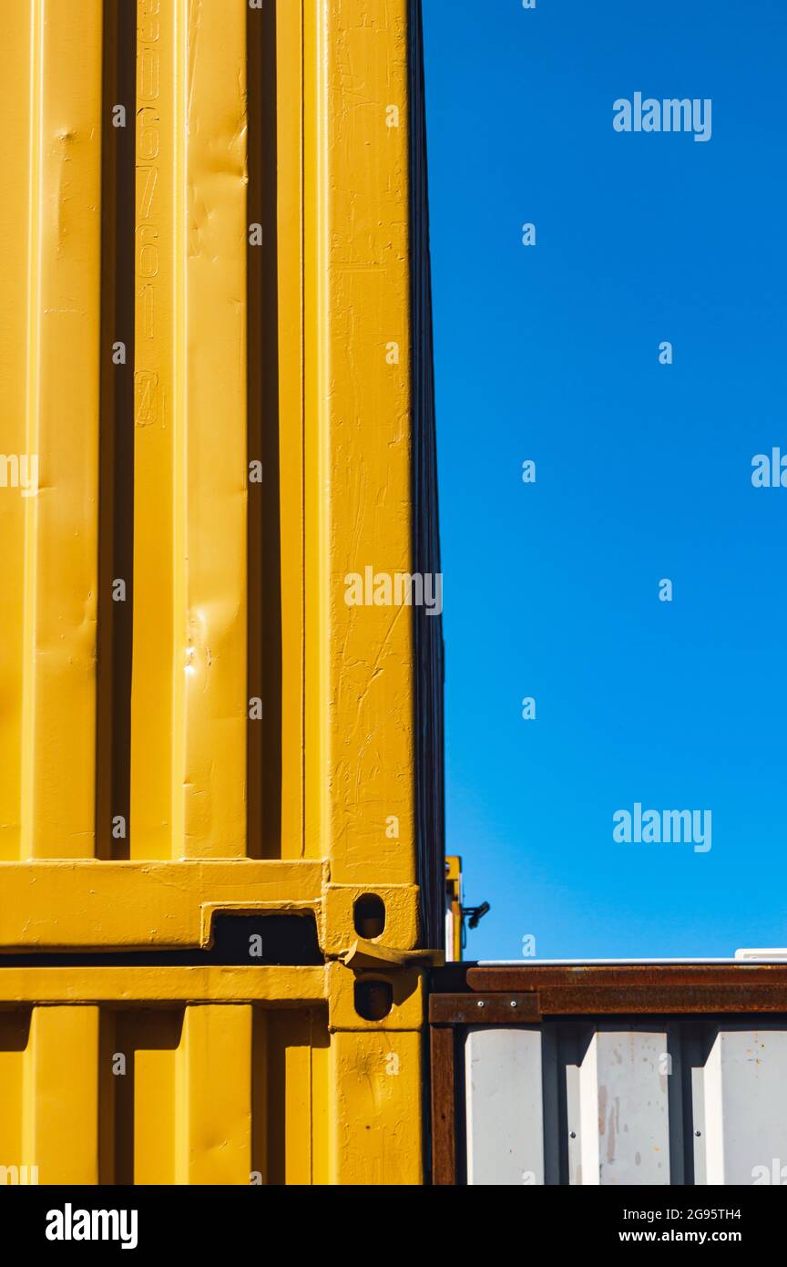 Vertical abstract image of stacked yellow shipping containers against a clear blue sky Stock Photo
