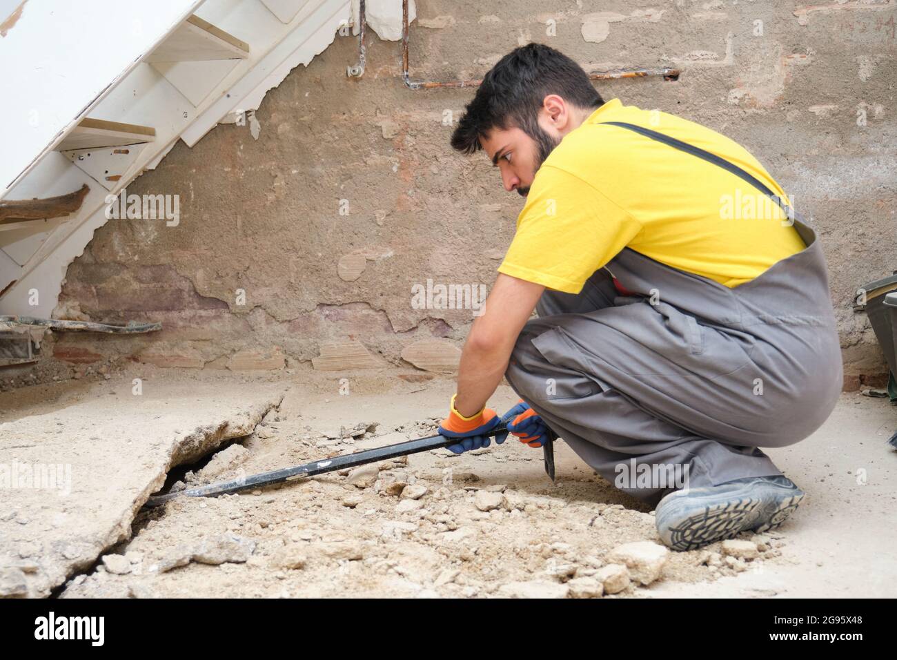 Young caucasian construction worker breaking up a house floor with