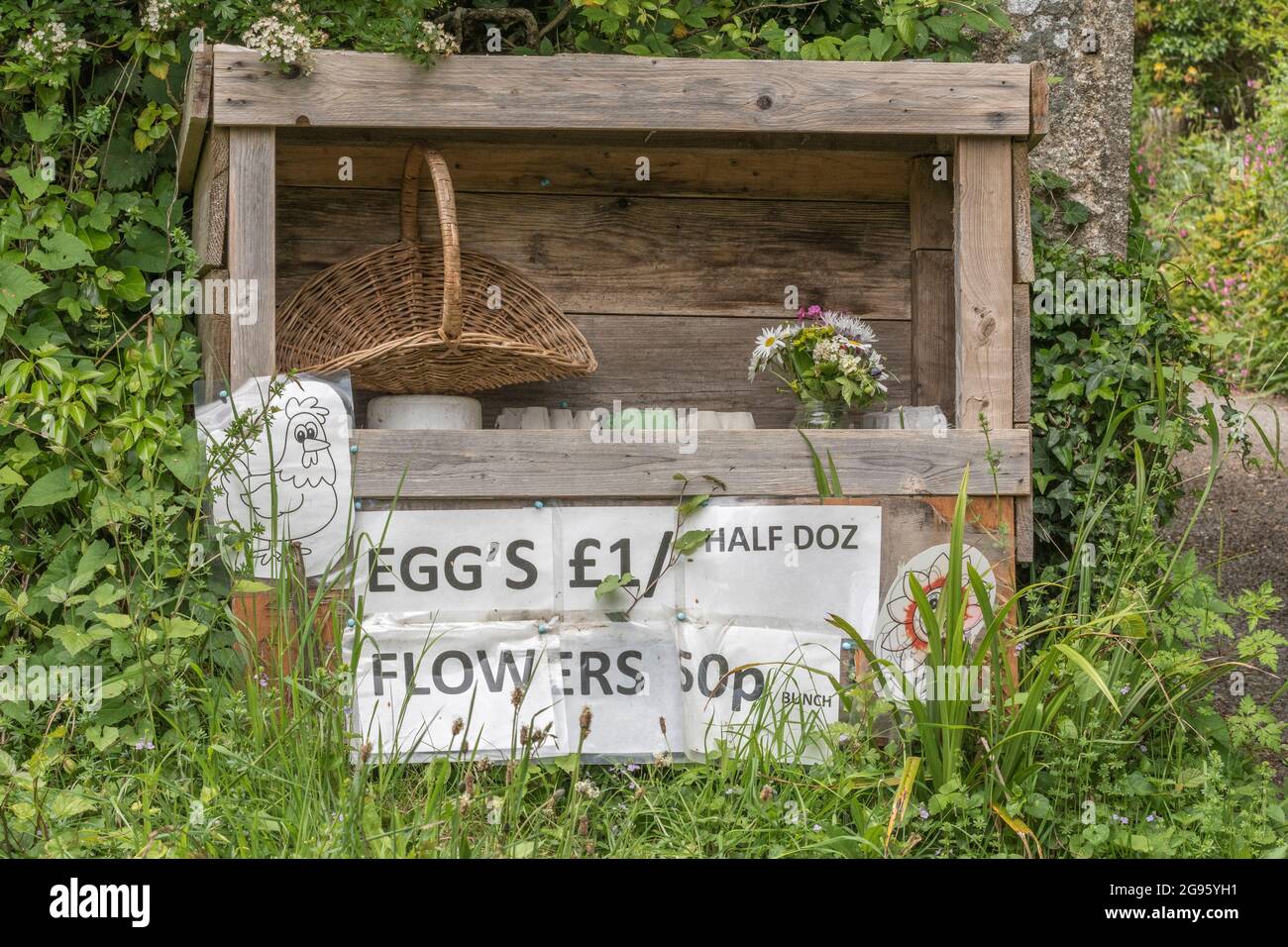 Stand at side of road selling flowers & free range eggs at £1 for half a dozen. For rural businesses, honesty box in countryside, life in the country. Stock Photo