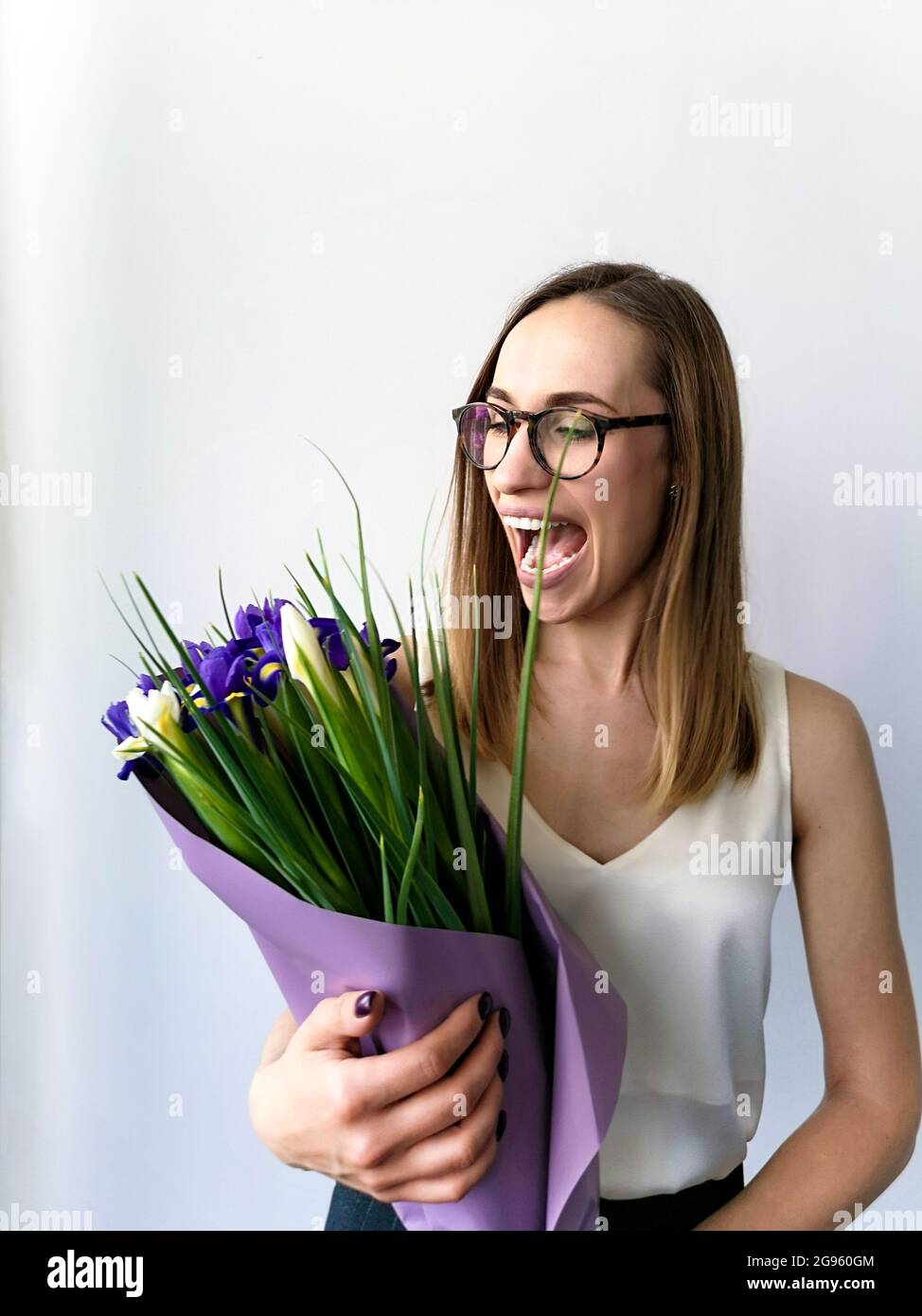Surprised woman with glasses looking at a bouquet of irises Stock Photo
