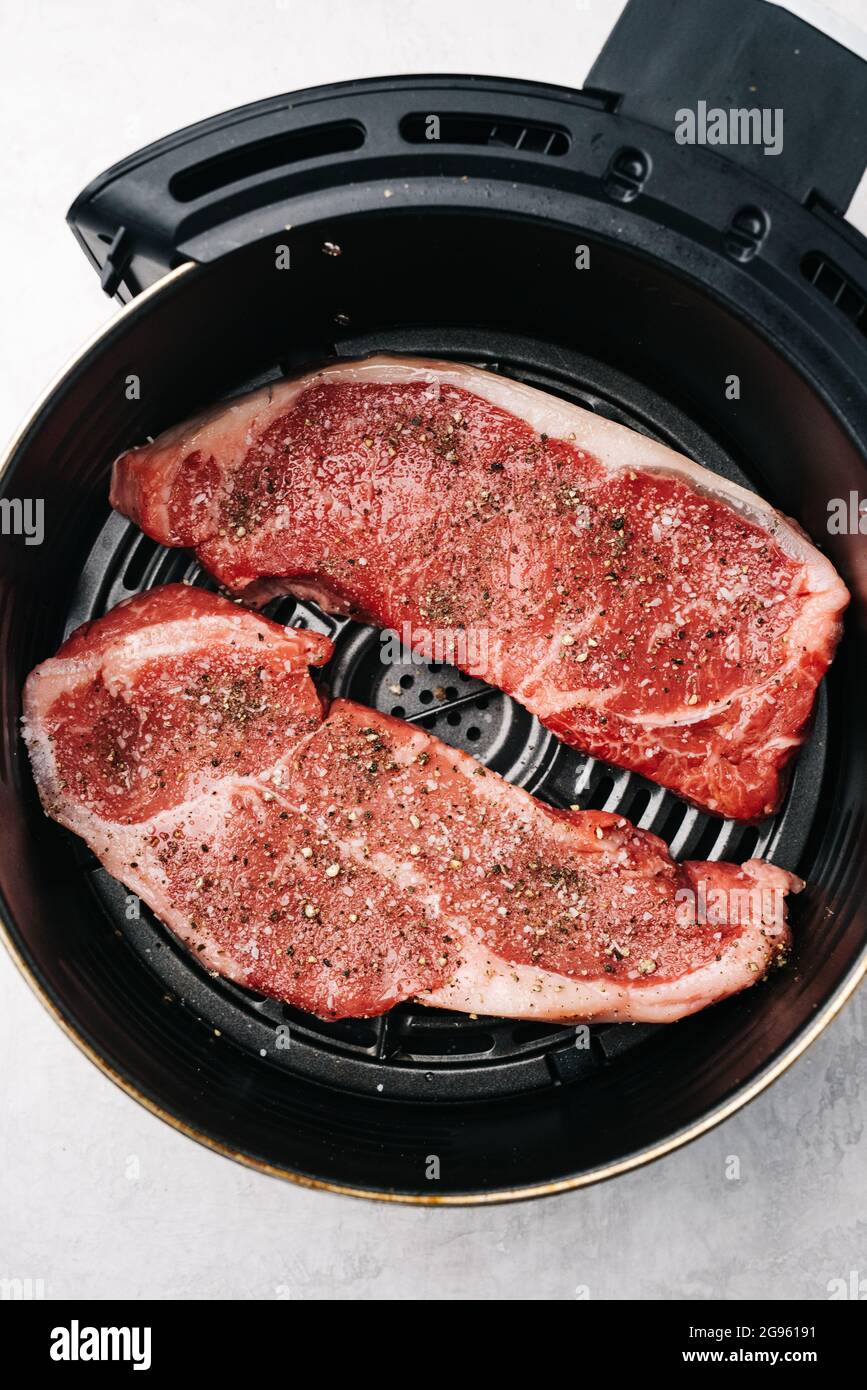 Raw flat iron steaks in an air fryer Stock Photo Alamy