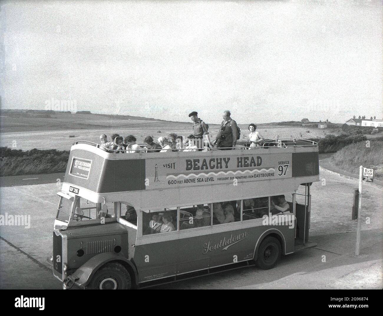 1950s, 'Visit Beachy Head'....people on an open-top double decker bus, a utility Guy Arab, service 97, parked at Beachy Head, a headland on the South Downs at Eastbourne, East Sussex. The highest chalk sea cliff in Britain, it's surrounding undulating downs are a famous spot for pleasure walking, with views over the English Channel. An area of outstanding natural beauty, in 1929, the land was purchased to safeguard its use for future generations. Southdown Motors operated the Route 97 from Royal Parade, Eastbourne, to the top of Beachy Head, a service for daytrippers which dates back to WW1. Stock Photo