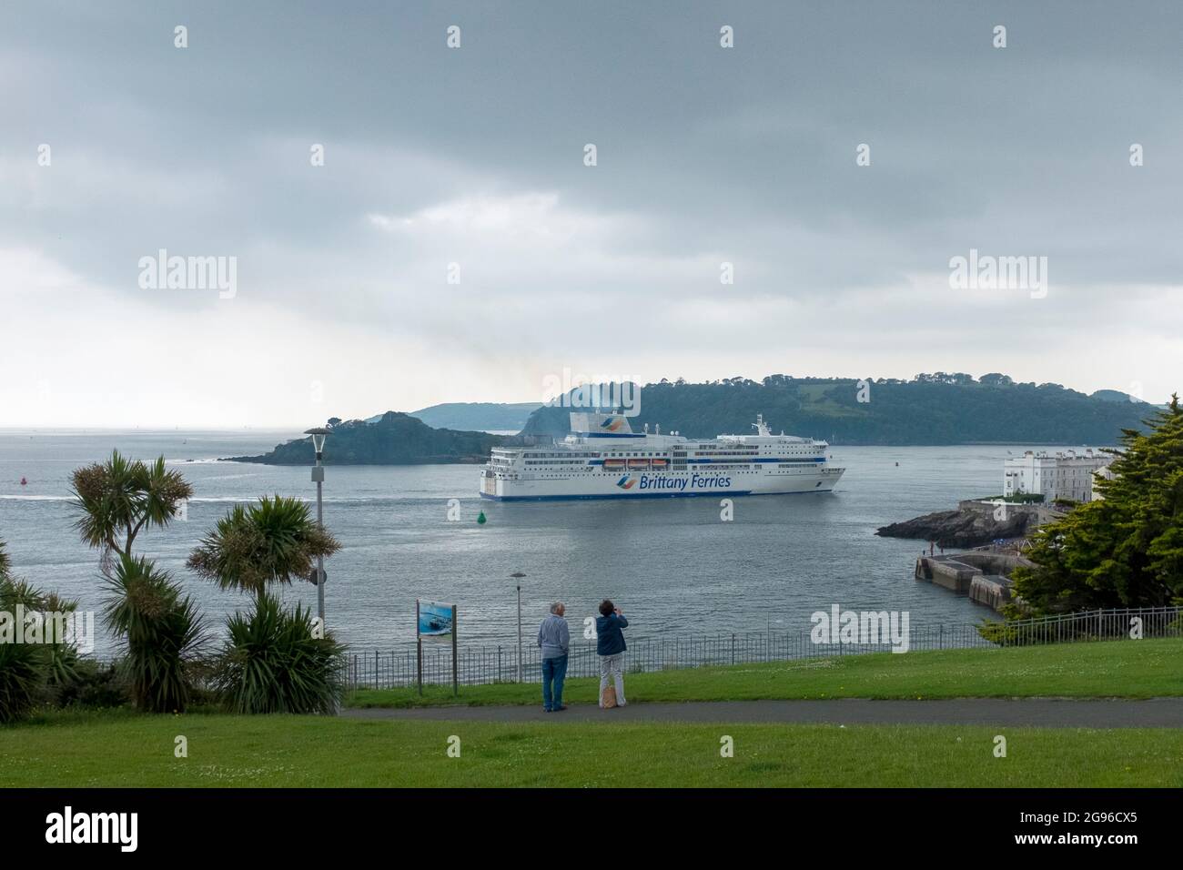 A Brittany Ferries ship heads towards the Brittany berth in Plymouth watched from Hoe Park by two people Stock Photo