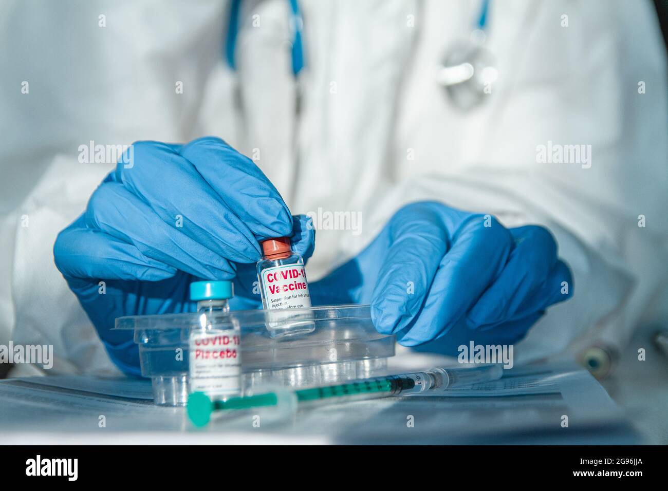 Doctor or nurse in protective suit holding covid 19 vaccine and placebo Stock Photo