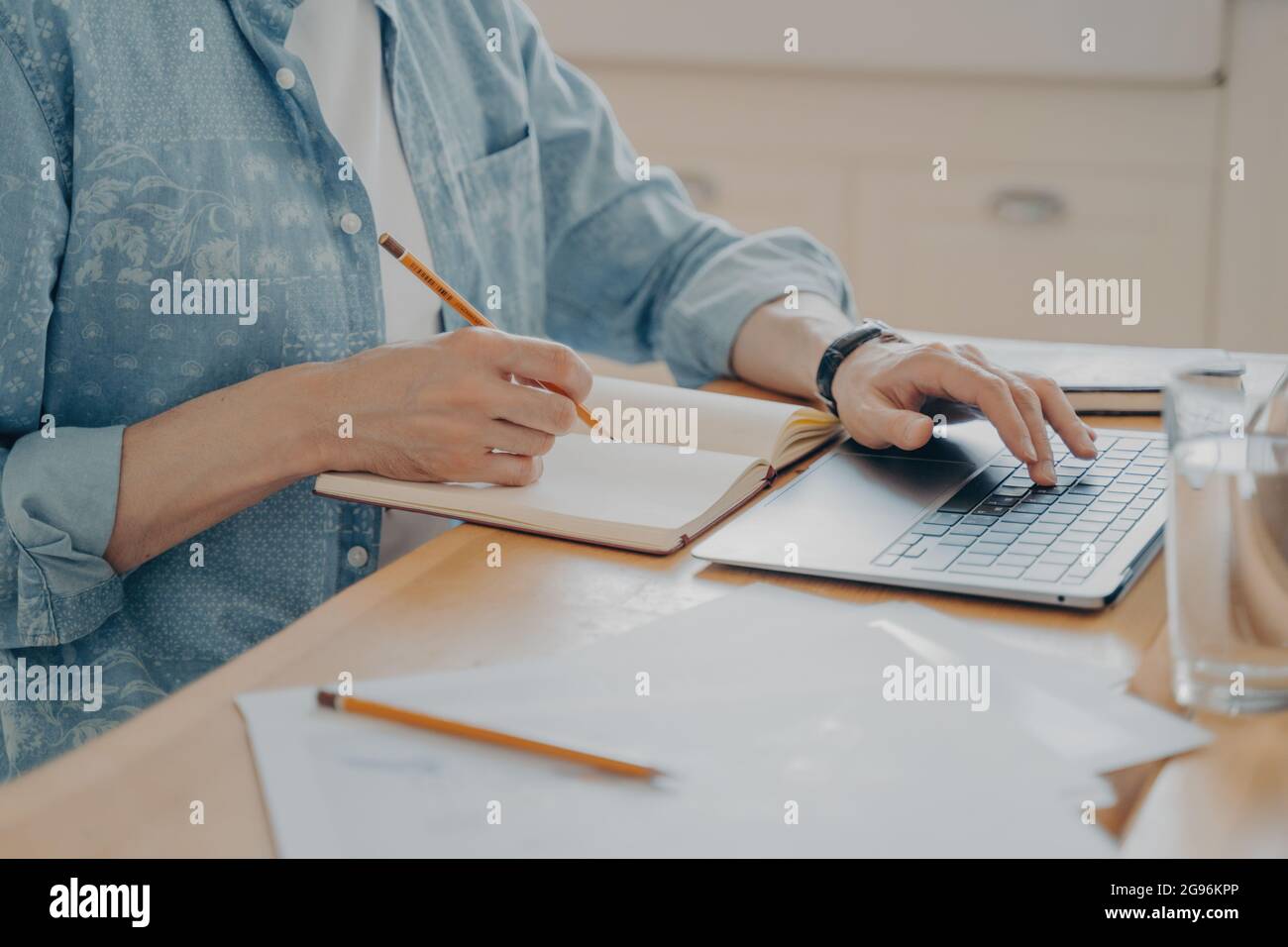 Man working at home remotely on laptop while sitting at his workplace, cropped shot Stock Photo